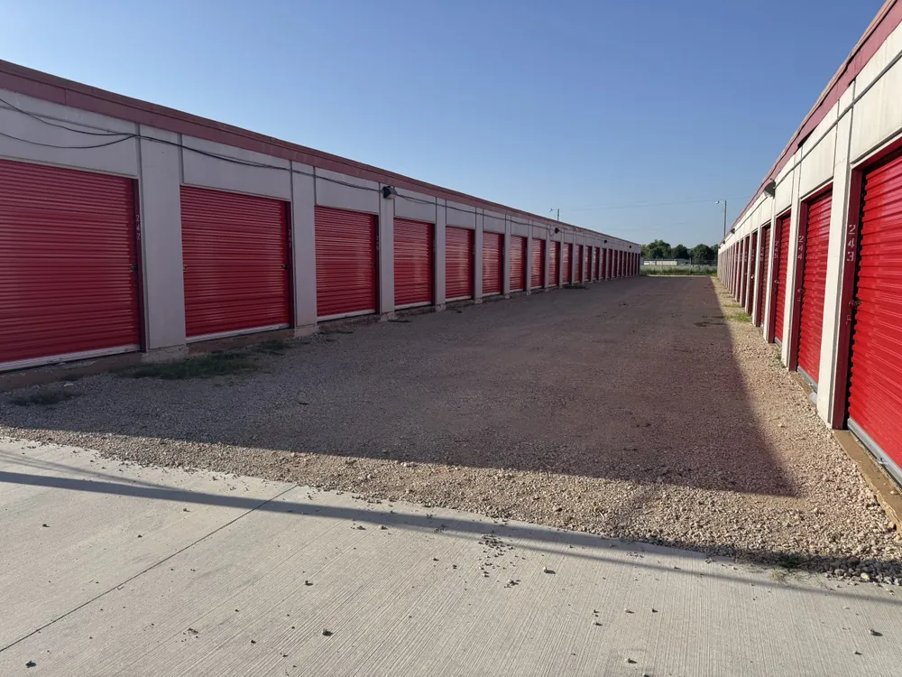 Wide gravel drive aisle between rows of drive-up storage units at Yukon Self Storage